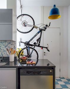 a bike hanging from the ceiling in a kitchen with blue and white checkered flooring