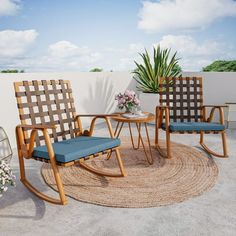 two chairs and a table on a patio with a potted plant in the corner