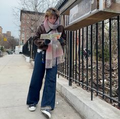 a woman standing on the sidewalk reading a newspaper