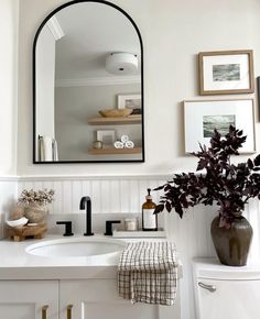 a bathroom sink with a mirror above it and a vase on the counter next to it