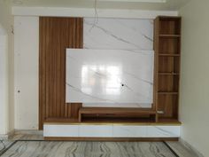 an empty living room with marble and wood accents on the wall, built in bookshelves