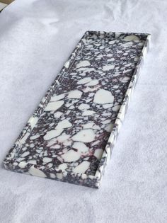 a white and black marbled tray sitting on top of a bed covered in sheets