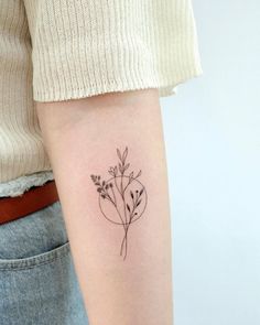 a woman's arm with a small flower tattoo on the left side of her arm