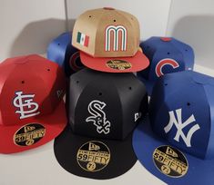 many different baseball caps are lined up in a row on the table, one is red, one is blue and one is black