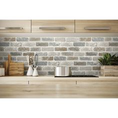 a kitchen counter with pots and utensils on it next to a brick wall