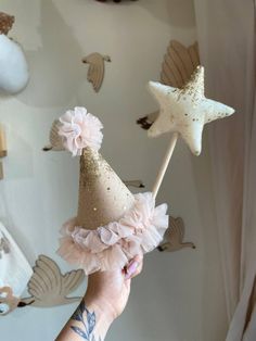 a hand holding a cake topper with stars on it and pink ruffles