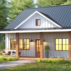 a small house with a metal roof in the middle of some grass and trees around it