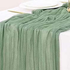 the table is set with plates and napkins on it, along with a green blanket