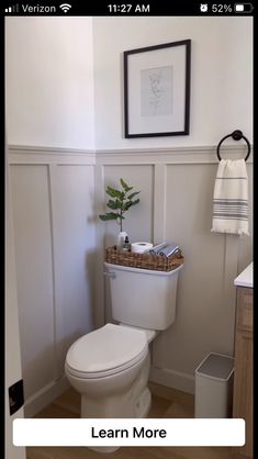 a white toilet sitting in a bathroom next to a wooden cabinet and framed pictures on the wall