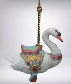 an ornament shaped like a swan hanging from a rope on a white background