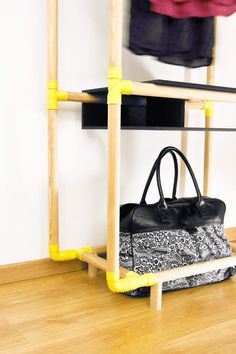 a black and white bag sitting on top of a wooden shelf next to a coat rack