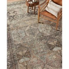 a large rug with an ornate design on the floor and two chairs in front of it