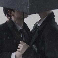 two people standing under an umbrella in the rain with their faces close to each other