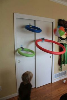 a little boy standing in front of a door with two frisbees hanging from it