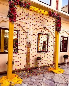 an outdoor wedding venue with flowers on the wall and yellow pillars, decorated with red roses