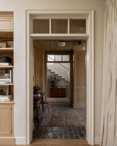 an open door leading to a living room and dining area with bookshelves on either side