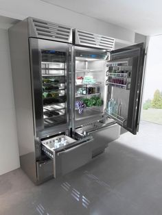 an open refrigerator with its doors wide open in a room that has concrete flooring and white walls