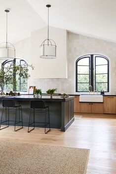 a large kitchen with two bar stools and an island in front of the sink