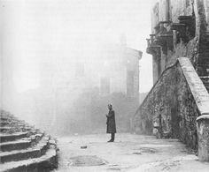 an old photo of a man standing in front of some stairs on a foggy day