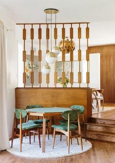 a dining room table with green chairs and a chandelier hanging from the ceiling