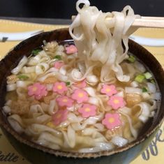 a bowl filled with noodles and vegetables on top of a table