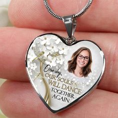 a person holding a heart shaped necklace with a photo on the front and back of it