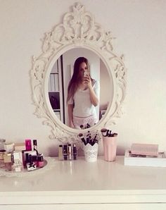 a woman taking a selfie in front of a mirror with her hair and makeup brushes