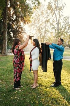 a man and woman holding up clothes while standing in the grass