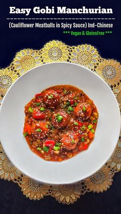 a white plate topped with meat covered in sauce next to a doily on top of a table