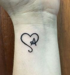 a heart with an arrow tattoo on the wrist