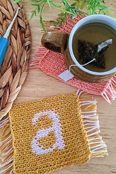 a cup of coffee sitting on top of a table next to a knitted coaster