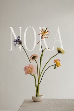 a vase with flowers in it sitting on top of a table next to the word nora