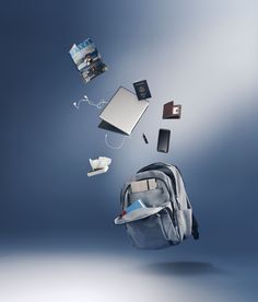 a backpack flying through the air with various items coming out of it