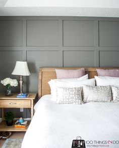 a white bed sitting in a bedroom next to a night stand with two lamps on top of it