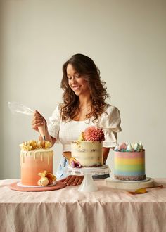 a woman holding a knife in front of two cakes