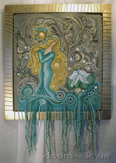 an art piece is hanging on the wall in front of a white curtain with blue and gold designs