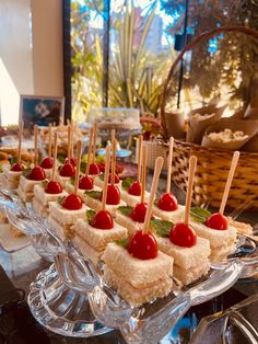 small sandwiches with cherries and mint on them are lined up on a glass platter