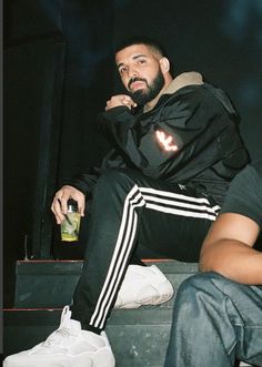 a man sitting on top of a step next to another person holding a beer bottle