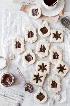 cookies with chocolate frosting are arranged on a table next to a cup of coffee