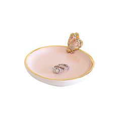 two wedding rings in a pink and gold ring dish with a butterfly on the side