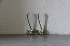 two metal hooks on the side of a wall