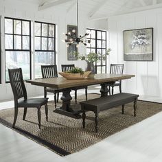 a dining room table with chairs and bench in front of large windowed area rug