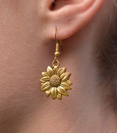 New Handmade Sunflower Dangle Earrings Sunflowers  yearn for light, symbolizing health, happiness, vitality, pursuing a positive life, and always have a positive attitude. Sunflower represents the courage to pursue the happiness you want. ~ 14k gold over sterling silver ear hooks  ~ Drop length 1.5 inches ~ Gold tone stainless steel Sunflower charm ~ Hypoallergenic  ♡ Also available in silver in my Etsy store. ☆I ship daily Monday-Saturday☆ Gift Packaging & Messages: Your item will be lovingly p Vintage Gold Earrings With Flower Charm, Anniversary Gold Jewelry With Sunflower Design, Brass Drop Earrings With Flower Charm, Sunflower Design Floral Jewelry, Flower Shaped Brass Jewelry With Matching Earrings, Nickel Free Brass Flower Earrings, Gold Sunflower Dangle Jewelry, Nickel-free Brass Flower Earrings, Elegant Gold Flower Earrings With Sunflower Design