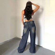 a woman standing in front of a white wall with her back turned to the camera