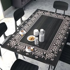 the table is set with two cups and plates of food, along with four black chairs