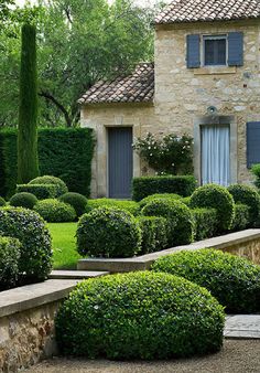 a stone house surrounded by lush green bushes