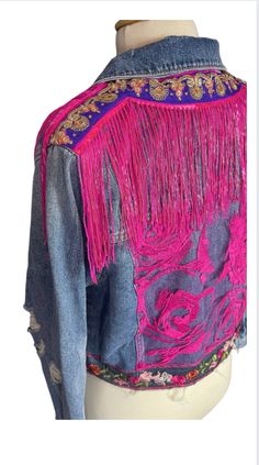 a denim jacket with pink fringes and flowers on the back, sitting on a mannequin head