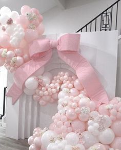 pink and white balloons in the shape of a house with a large bow on top