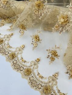 an embroidered lace with flowers and pearls on white fabric, sitting on a tablecloth