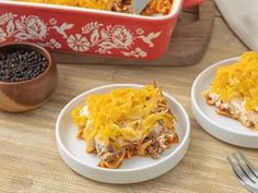 two white plates topped with food next to a red casserole dish